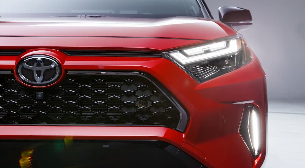 Close-up on the headlights and grille of a red 2025 Toyota RAV4 PHEV.