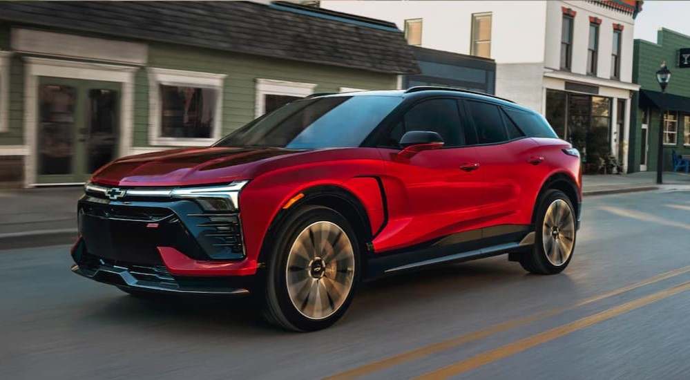 A red 2025 Chevy Blazer EV RS is shown driving on a city street.