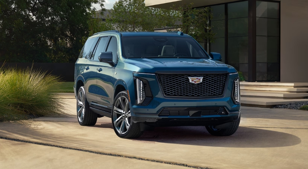 A blue 2025 Cadillac Escalade parked in front of a house.