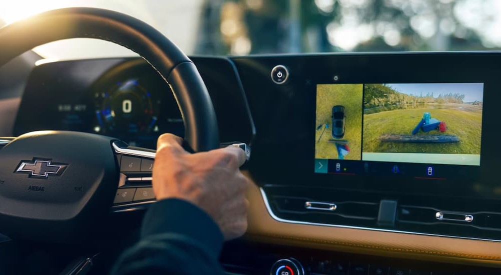 A close-up of a steering wheel and infotainment screen is shown in a 2025 Chevy Equinox for sale.