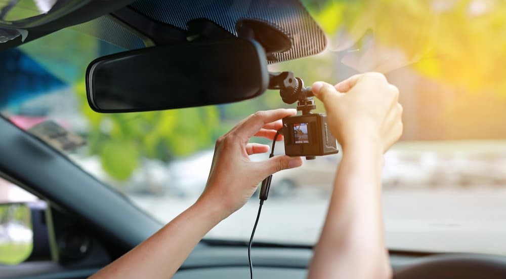 A person is shown installing a dash cam.