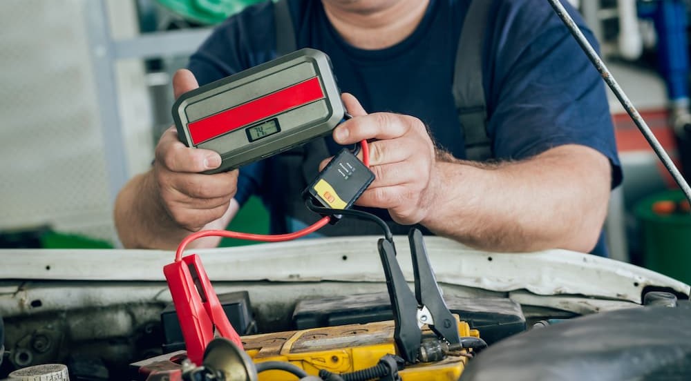 A person is shown holding a portable jump starter