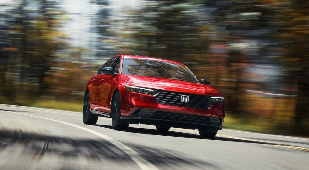 A red 2025 Honda Accord Sport L Hybrid driving around a bend.