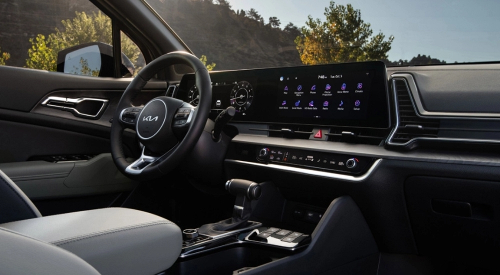 The steering wheel and infotainment screen in a 2025 Kia Sportage X-Pro Prestige at a Kia dealer.