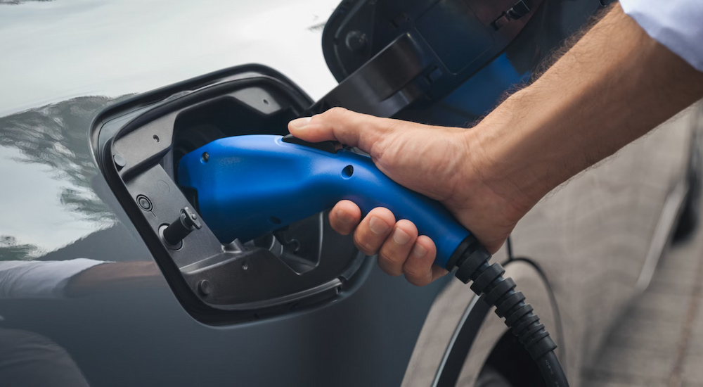 Close-up of a driver plugging in a silver 2025 Toyota Prius Plug-In XSE Premium to charge.