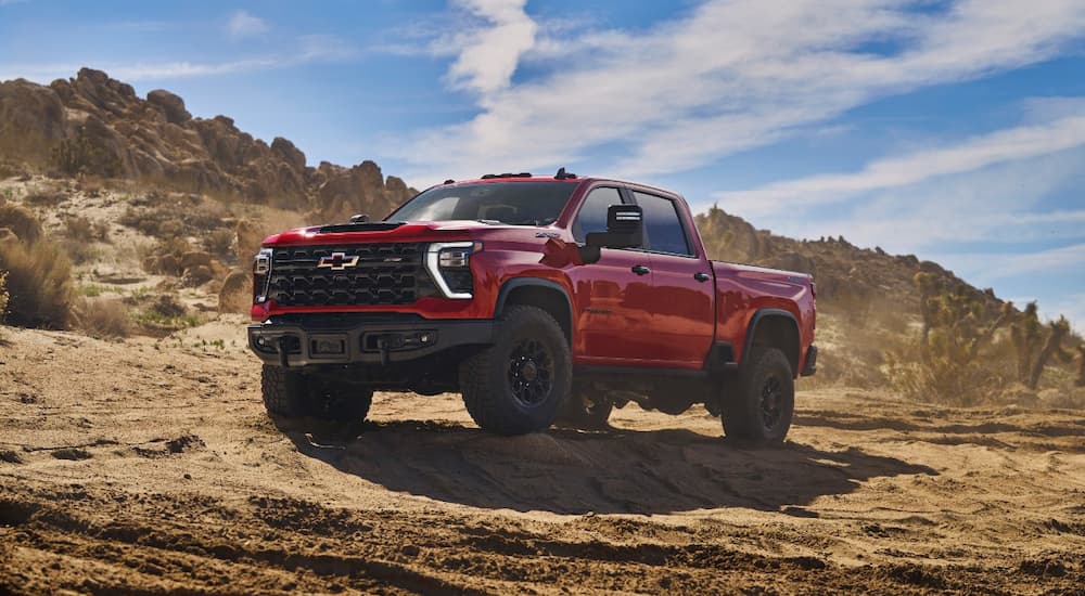 A red 2023 Chevy Silverado HD ZR2 Bison off-roading in a desert area.