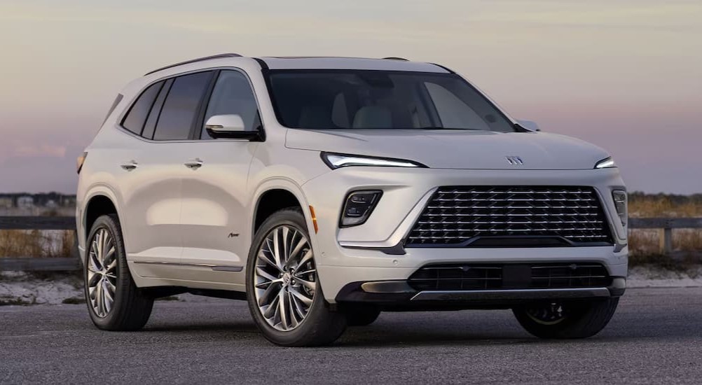 A white 2025 Buick Enclave Avenir is shown parked near a beach.