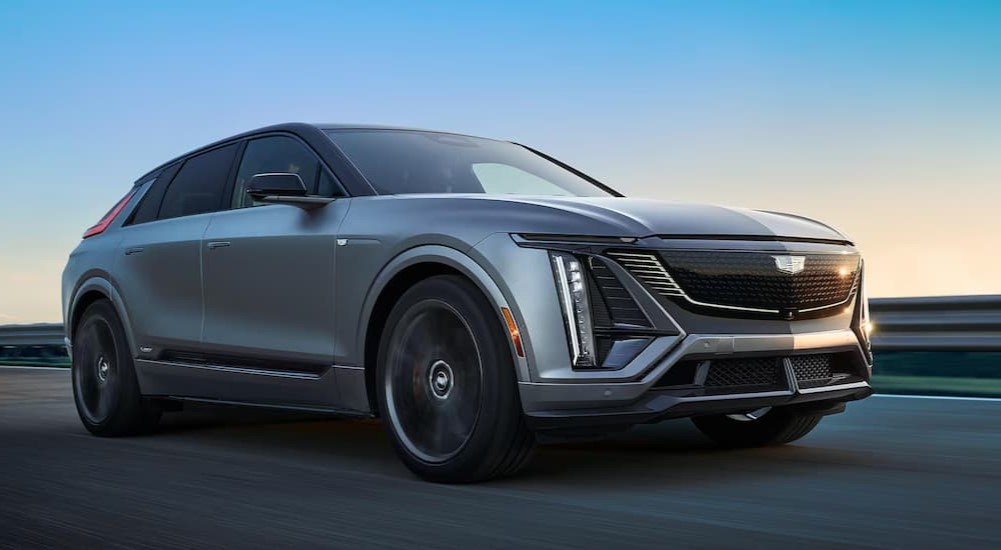 A silver 2026 Cadillac LYRIQ-V is shown driving on a highway.