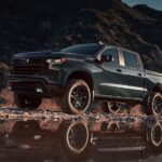 A green 2025 Chevy Silverado 1500 Z71 for sale is off-roading on a rocky trail.