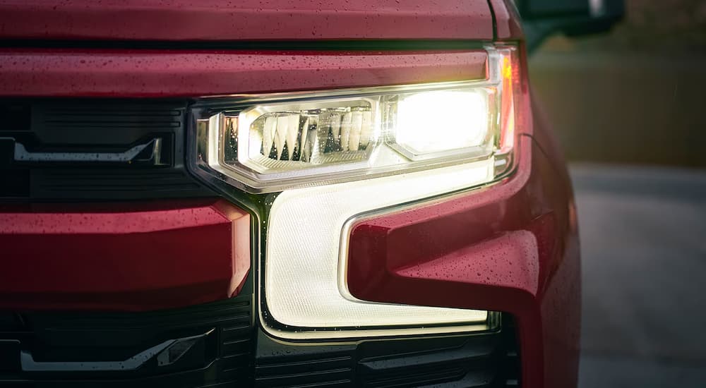 A close up of the headlight on a red 2024 Chevy Silverado 1500 RST.