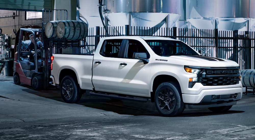 A white 2025 Chevy Silverado 1500 Custom Rally Edition is parked in a city at night.