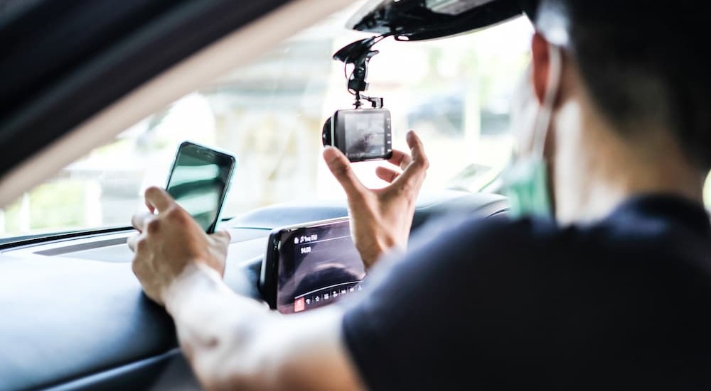 A person is shown installing a dash cam.