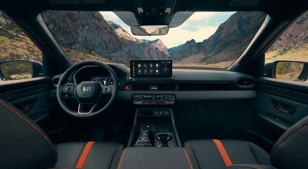 The black and orange interior of a 2026 Honda Passport TrailSport at a Honda dealer.