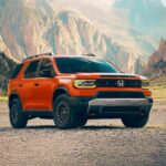 An orange 2026 Honda Passport TrailSport parked in an open valley.