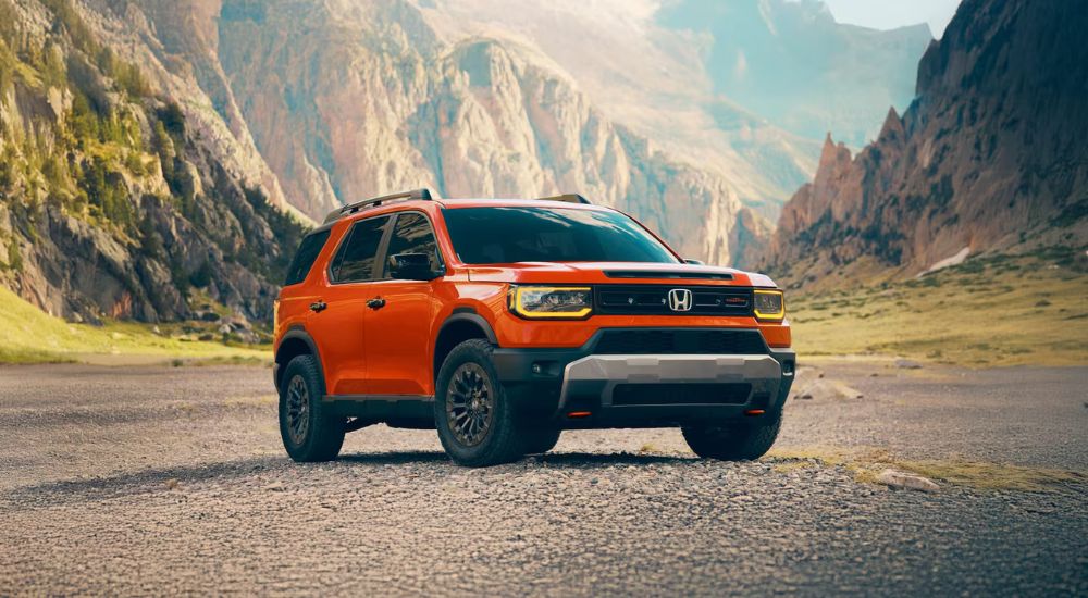 An orange 2026 Honda Passport TrailSport parked in an open valley.