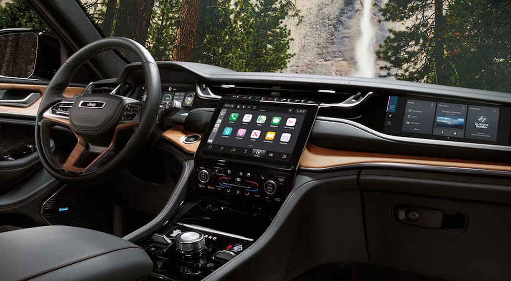 Angled view of the steering wheel and dashboard in the black and brown interior of a 2025 Jeep Grand Cherokee L.