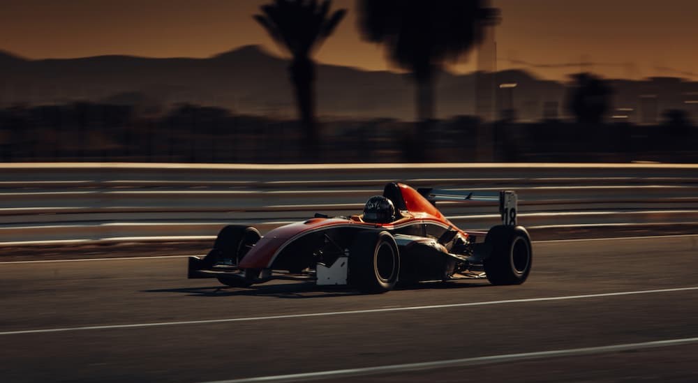 A racecar is shown driving on a track.