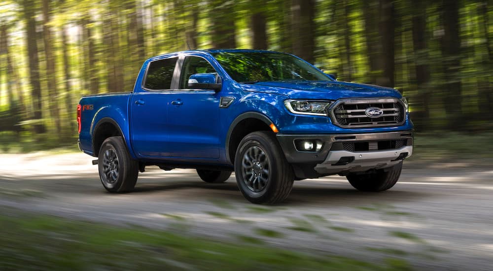 A blue 2019 Ford Ranger is shown driving on a dirt road after visiting a used car dealer.