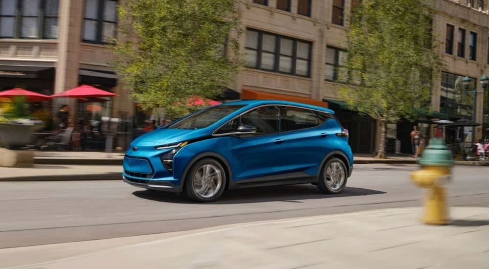 A blue 2023 Chevy Bolt EV is shown driving after viewing used EVs for sale.