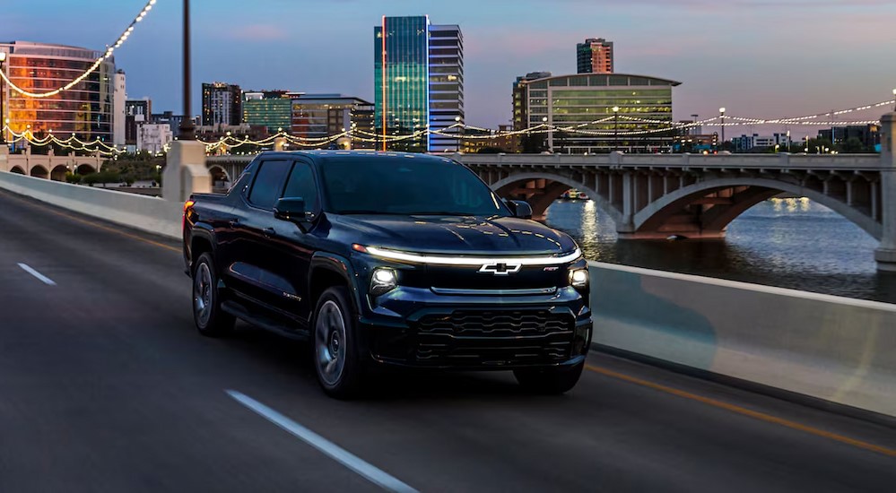 A black 2024 Chevy Silverado EV RST is shown driving on a bridge.