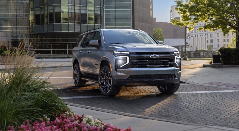 A silver 2025 Chevy Tahoe RST driving through the city to find a "car dealer near me."