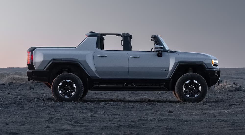 A grey 2025 GMC Hummer EV Pickup, a popular EV for sale, is parked on gravel.