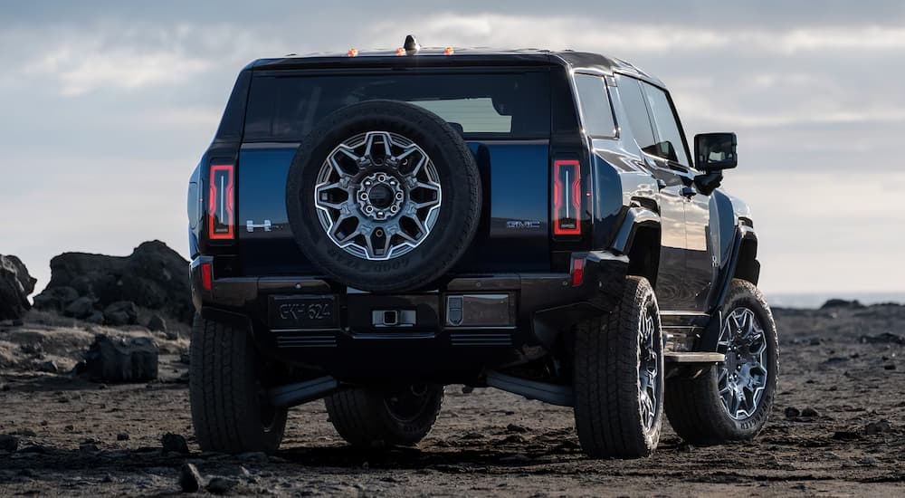 A rear view of a 2025 GMC EV SUV on an open rocky and dirt area.