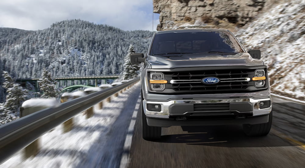 Front angle view of a grey 2025 Ford F-150 for sale driving on a mountain.