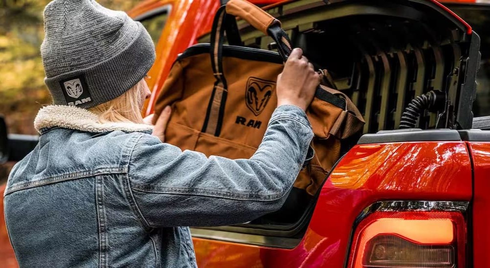 A person is shown utilizing the Rambox in a red 2025 Ram 1500.