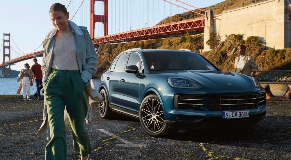 A blue 2025 Porsche Cayenne E-Hybrid parked under the Golden Gate Bridge.